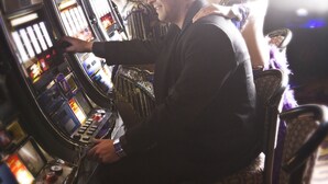 A slot machine area with illuminated screens and a person playing.