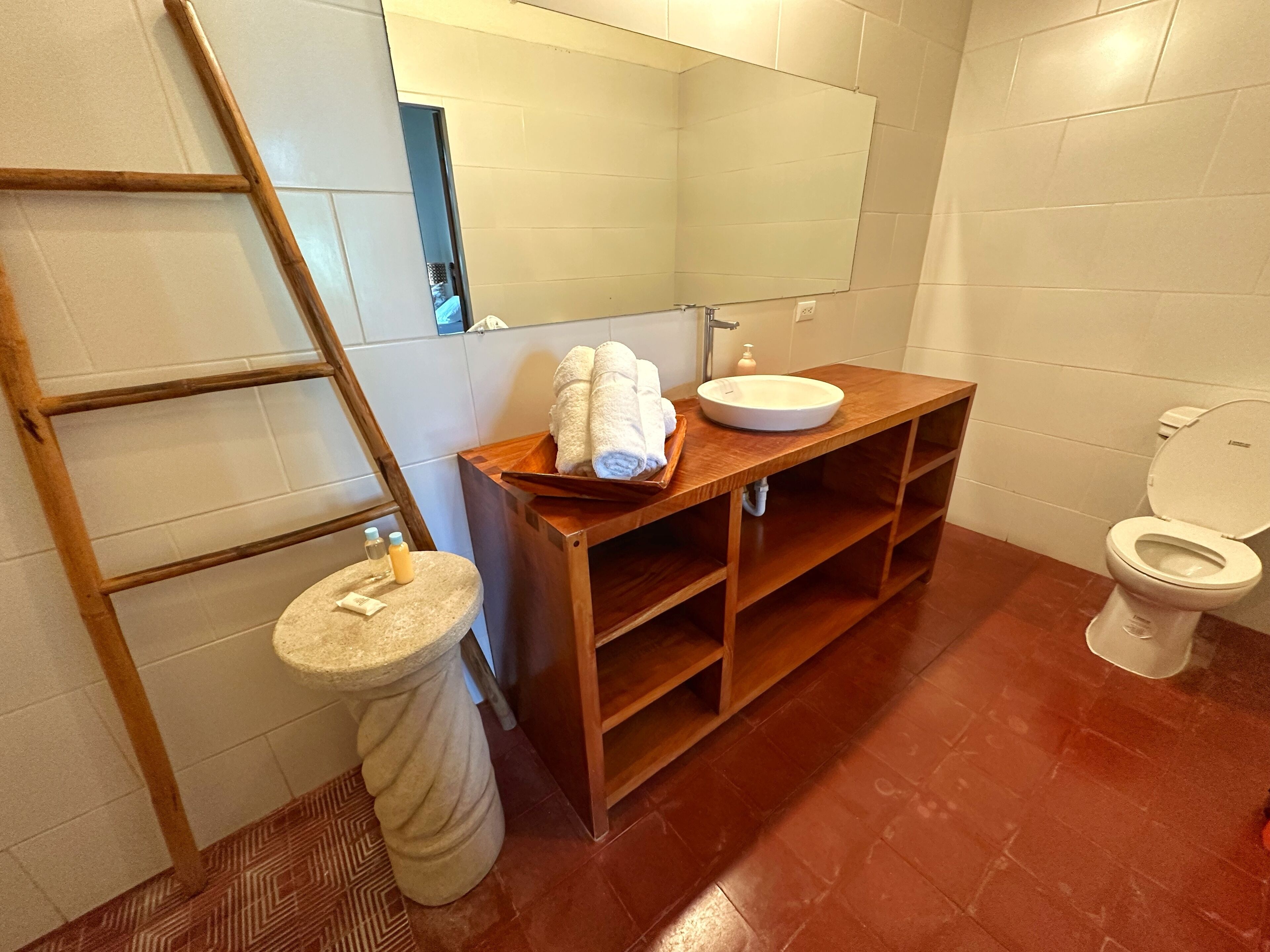A bathroom with a wooden vanity, a sink, a toilet, and a mirror.