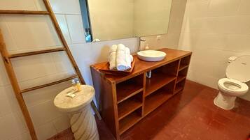 A bathroom with a wooden vanity, a sink, a toilet, and a mirror.