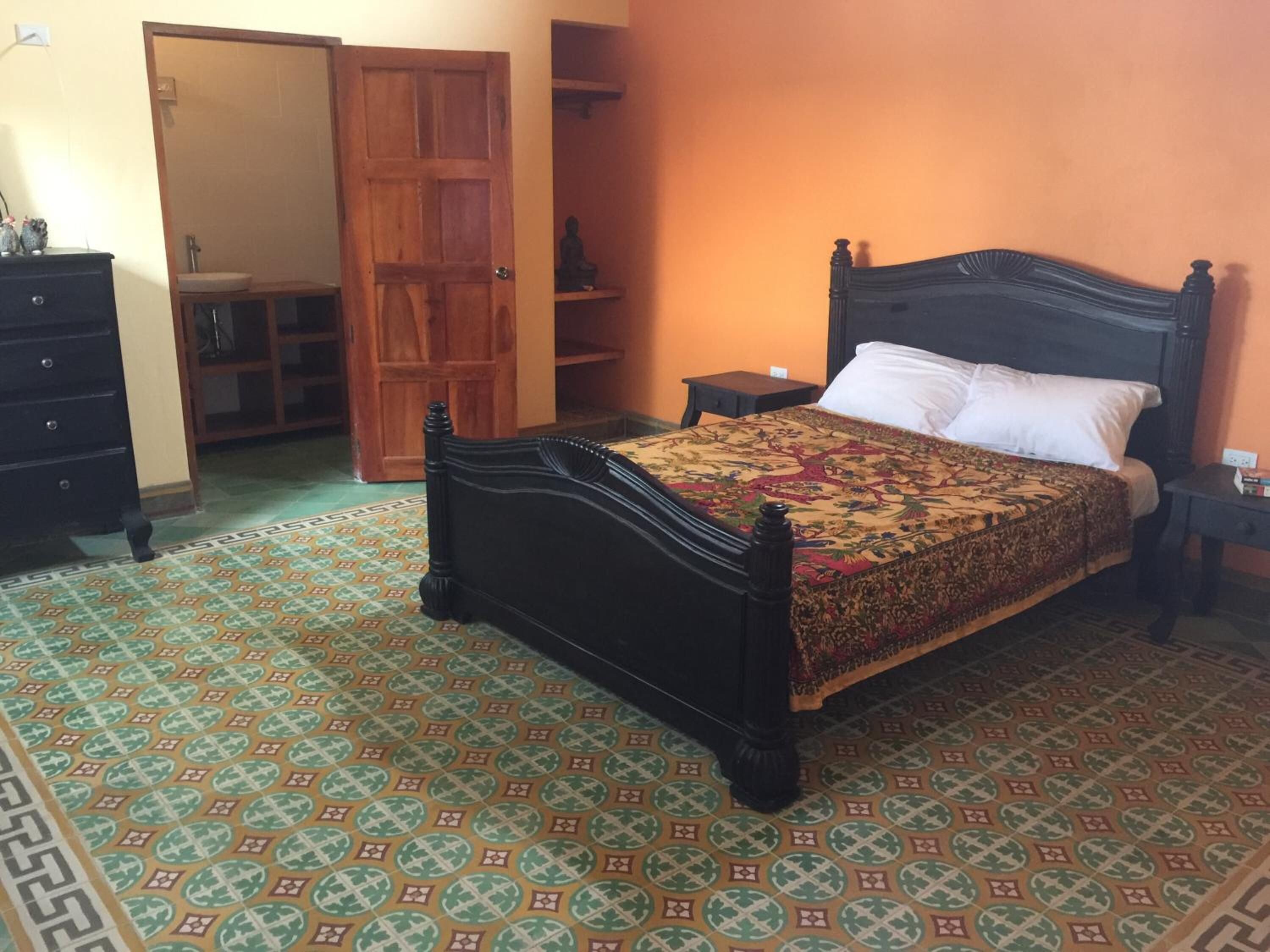 A bedroom with a wooden bed, a wardrobe, a small table, and a nightstand.
