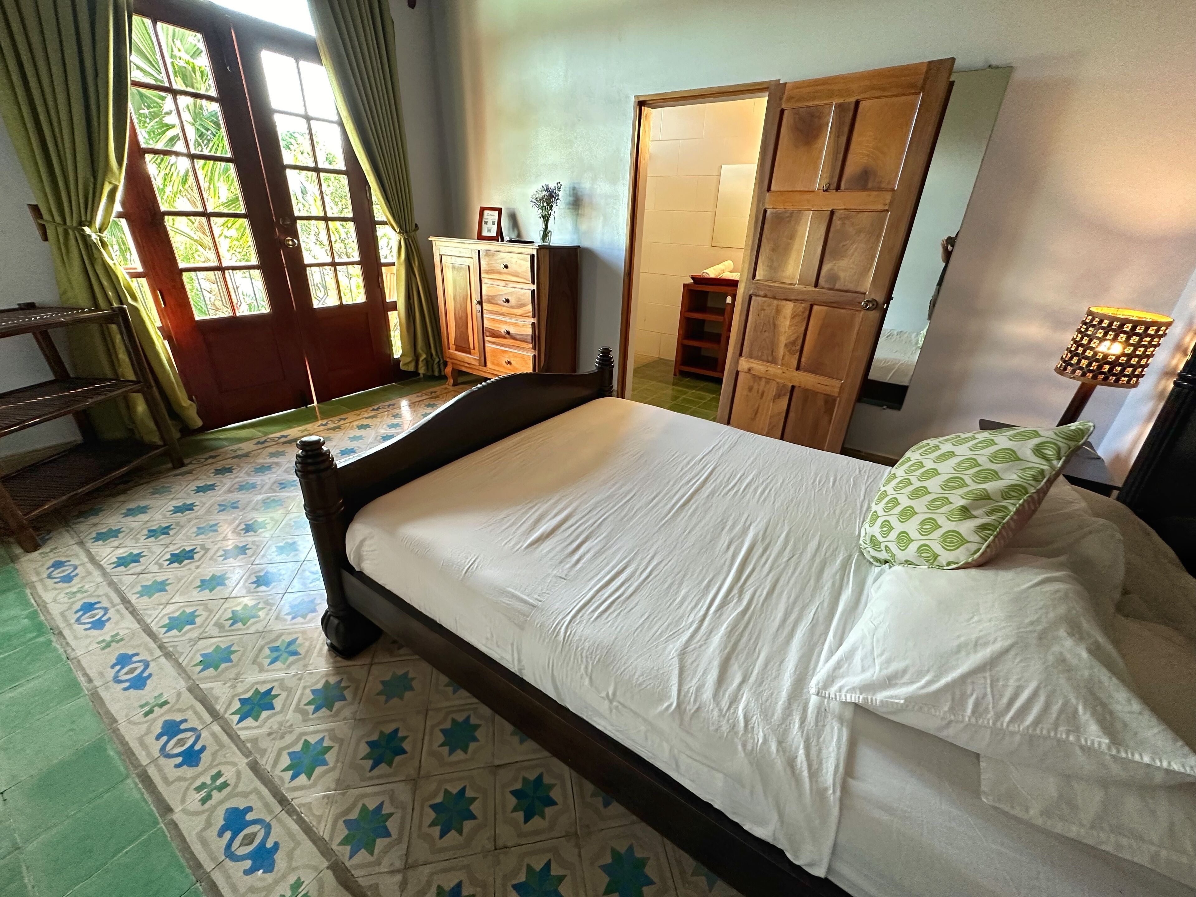 Un dormitorio con cama, cómoda, armario y lámpara.