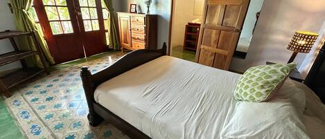 Un dormitorio con cama, cómoda, armario y lámpara.