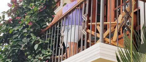 Een balkon met een balustrade, een houten trap en een raam met houten kader.