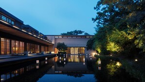 A modern building with a reflective water feature in front. - Numazu Club (Numazu)