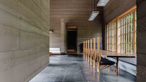 A corridor with a long table and chairs, a bench, and a door at the end. - Numazu Club (Numazu)