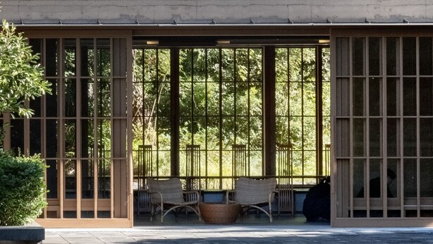 A modern building with large windows, a seating area with chairs and a table, and a reflective water feature in front. - Numazu Club (Numazu)
