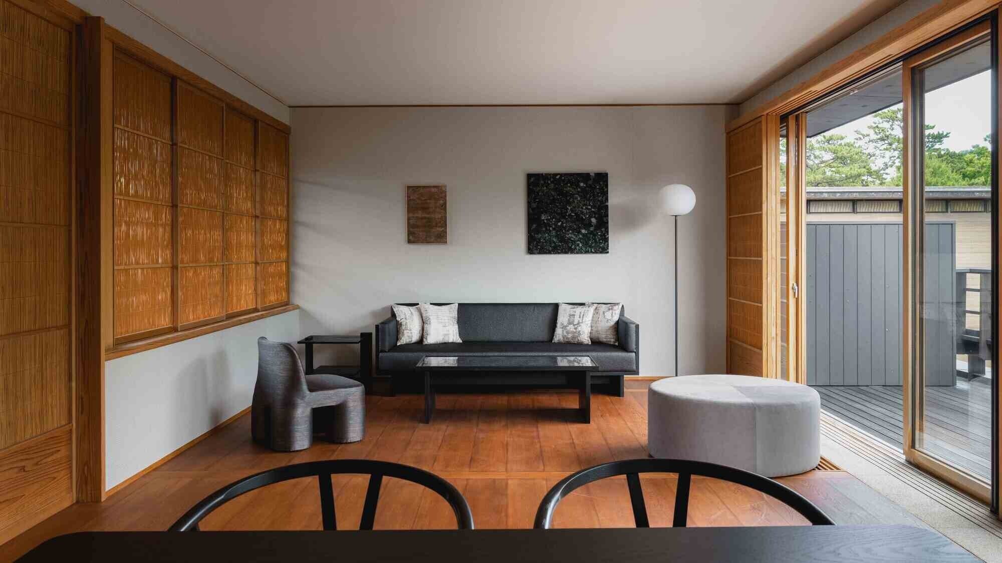 Una sala de estar moderna con un sofá, sillas, una mesa de centro y un ventanal grande.