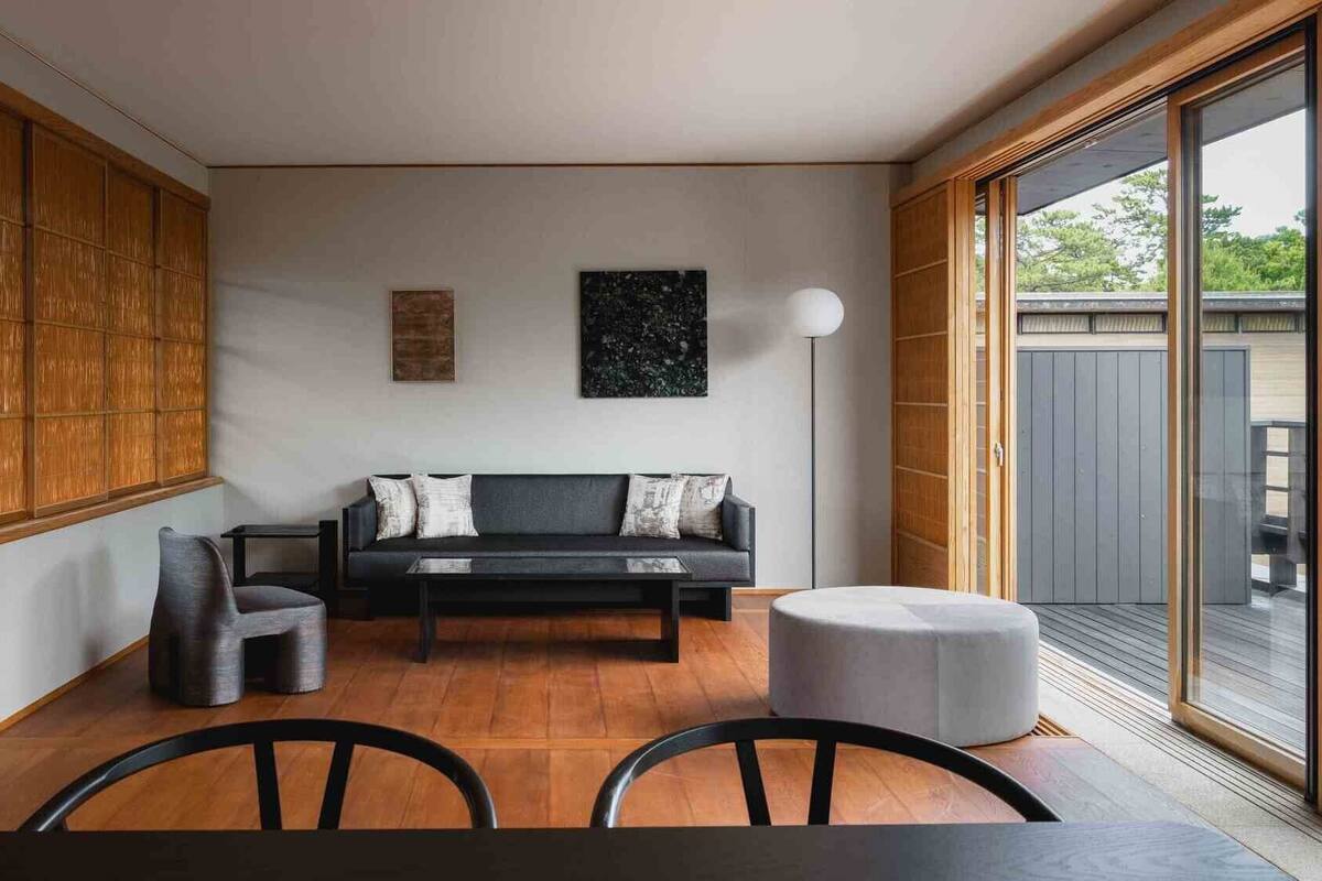 Una sala de estar moderna con un sofá, sillas, una mesa de centro y un ventanal grande.