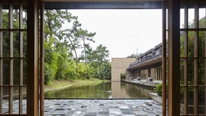 A view through open doors of a building with a water feature in front, surrounded by greenery. - Numazu Club (Numazu)