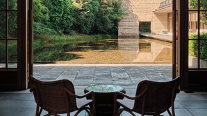 An indoor space with two wicker chairs facing a view of a garden and a water feature. - Numazu Club (Numazu)