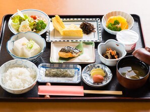 Una bandeja con diferentes platos japoneses, incluyendo arroz, tofu y verduras.