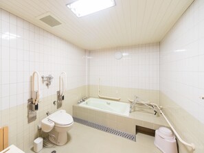 Un baño moderno con inodoro, lavamanos y bañera, equipado con barras de apoyo y asiento para ducha.