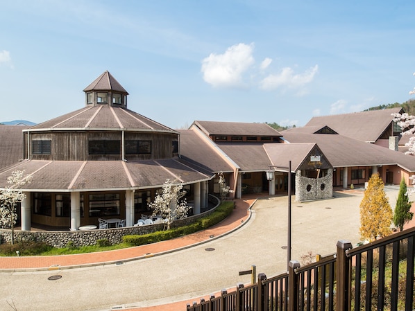 Un hotel con un patio central, varias edificaciones con techos a dos aguas y un muro de piedra que rodea el área.