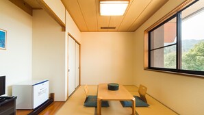 A room with tatami mats, a low table, a television, and a cabinet. - Gokurakuji Onsen Arcadia Village (Hatsukaichi)