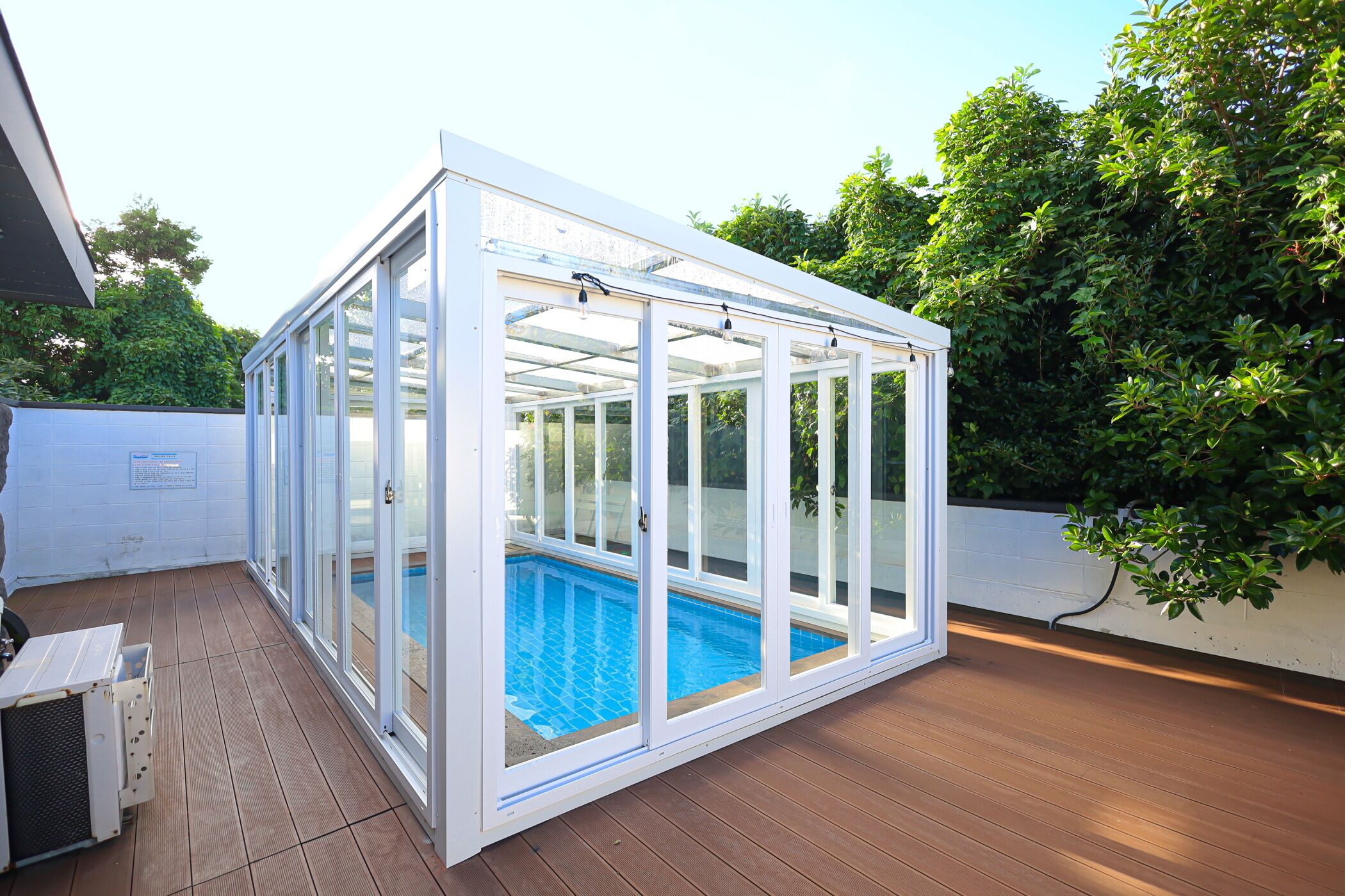 Una piscina cubierta con paredes de vidrio y una terraza de madera.