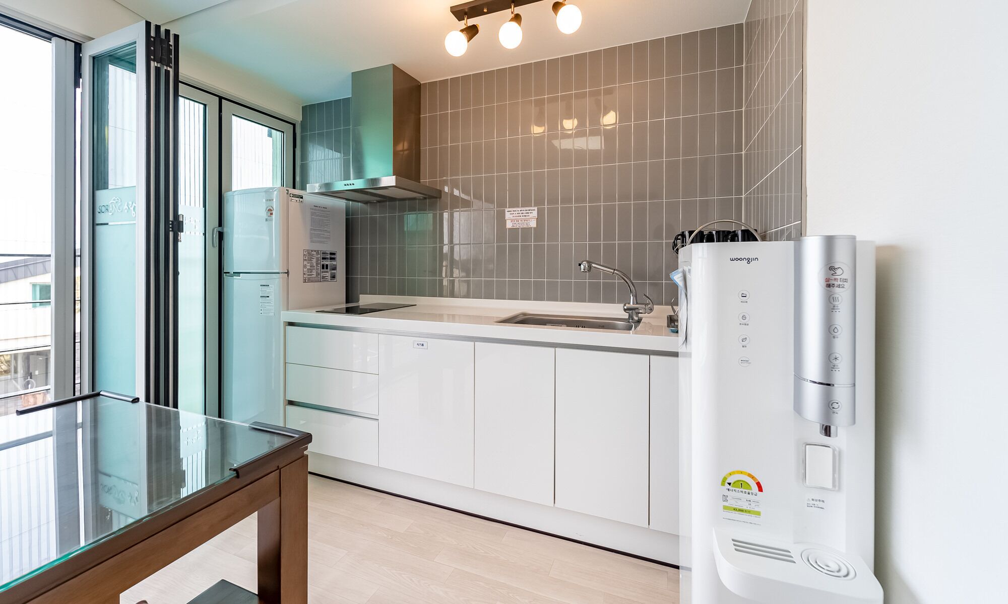 Una cocina moderna con horno empotrado, pileta y dispensador de agua.