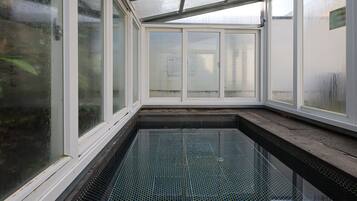 A glass-enclosed swimming pool with a tiled floor and a metal frame.