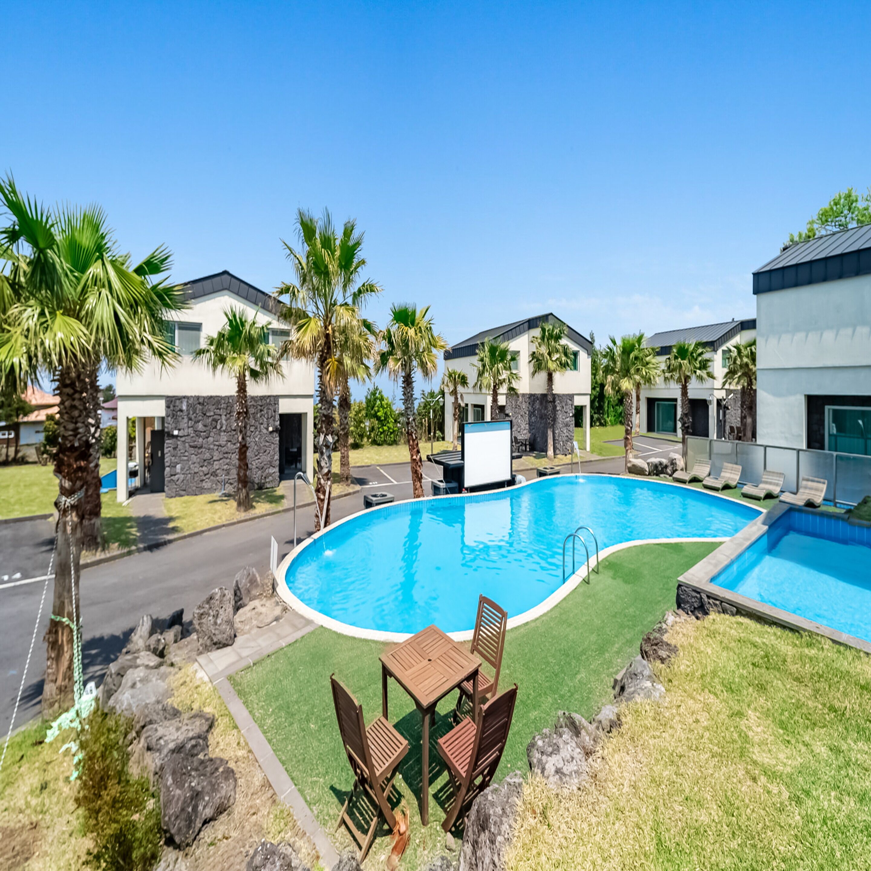 A swimming pool surrounded by palm trees and modern buildings.