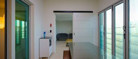 A corridor with a bench, a small table with a lamp, and a fire extinguisher on the wall.