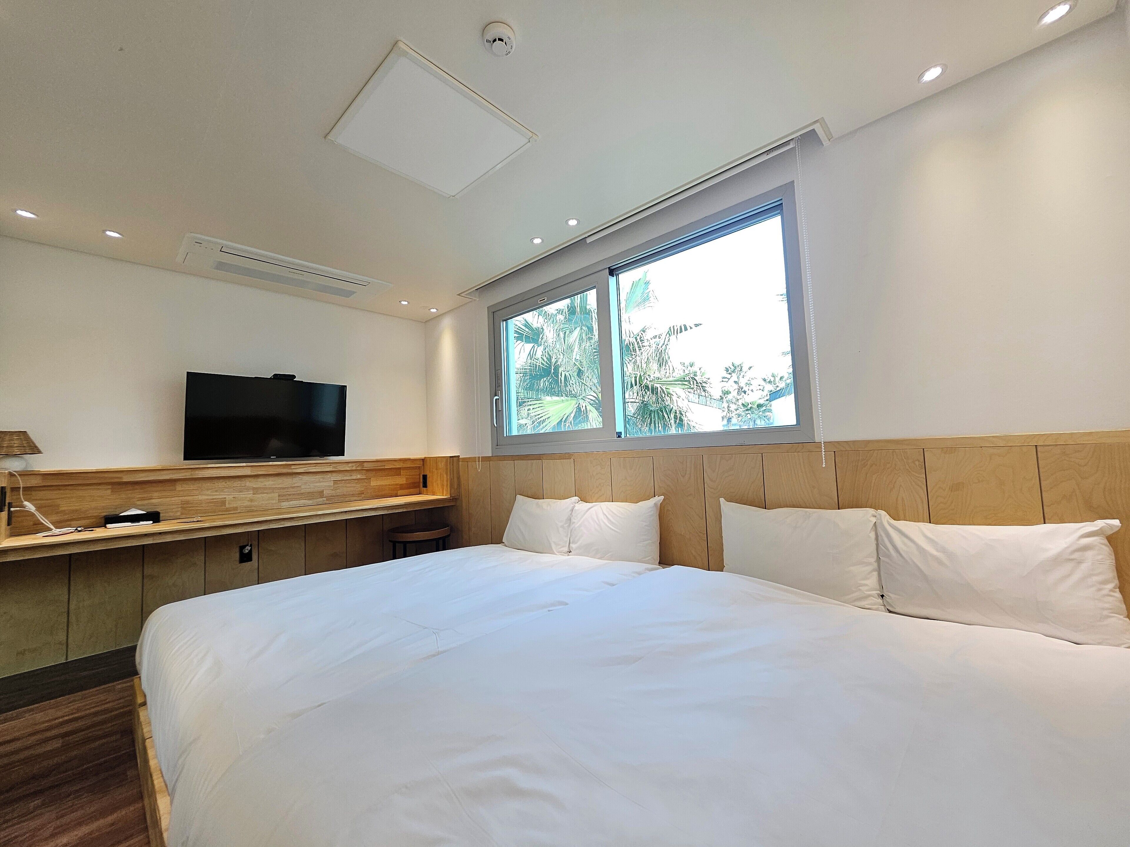 A hotel room with a bed, a TV, a window, and a desk.