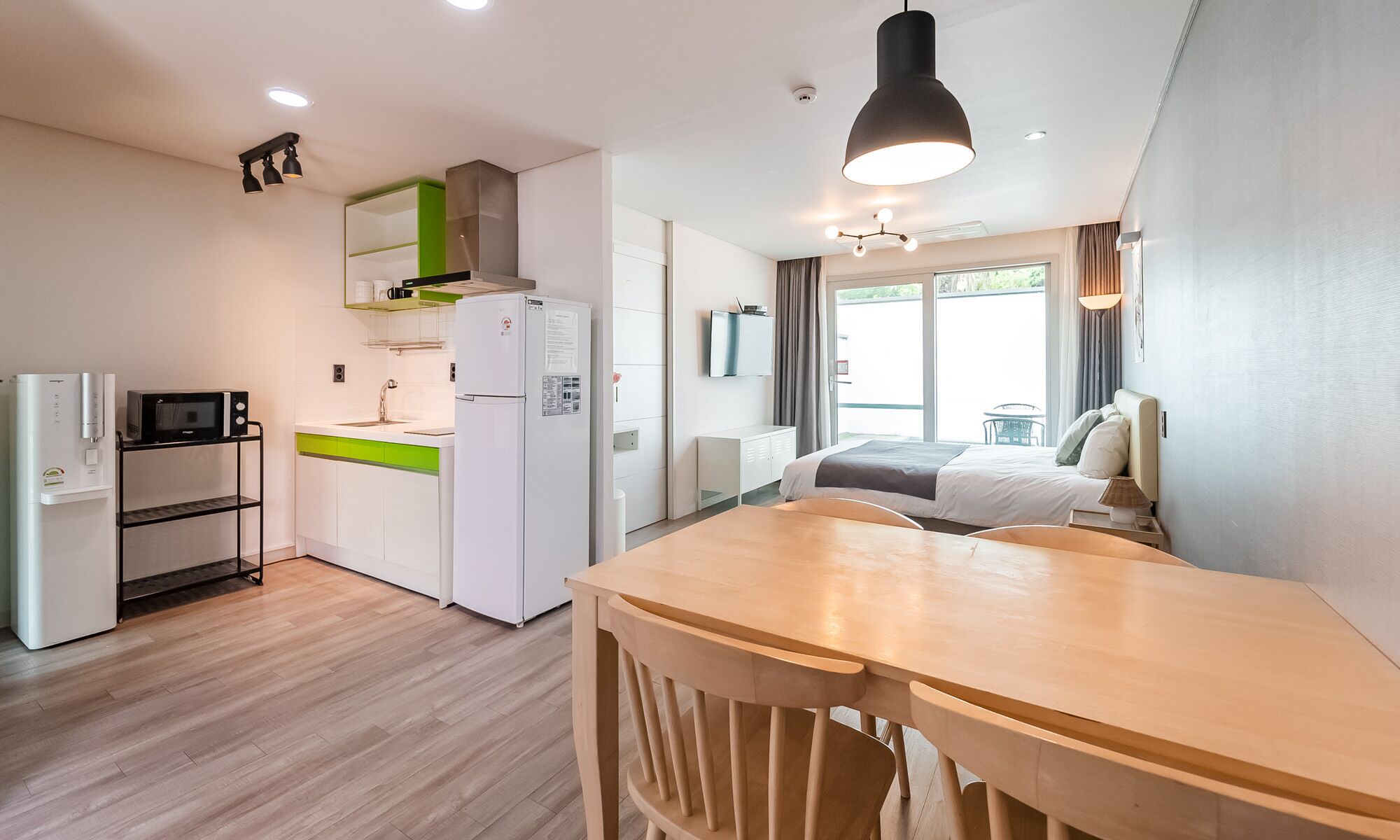 Habitación de hotel compacta con kitchenette, cama con vistas y comedor.