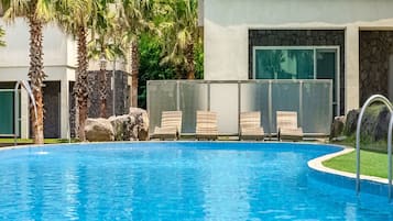 Una piscina al aire libre de temporada, sillones reclinables de piscina