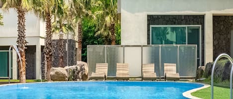 Una piscina al aire libre de temporada, sillones reclinables de piscina