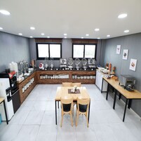 Una cocina moderna con una isla central, un comedor con cuatro sillas y una estación de café.