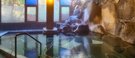 A hot spring area with stone walls and a glass barrier.