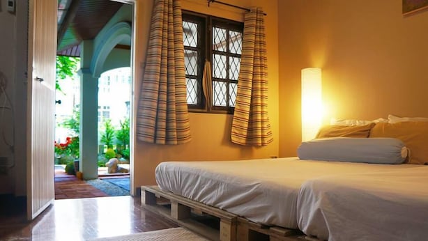 A bedroom with a bed, wooden floor, and a window with curtains. - Sleepy Oho (Chiang Mai)
