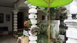 A room with a green umbrella, white columns, and flower planters. - Sleepy Oho (Chiang Mai)