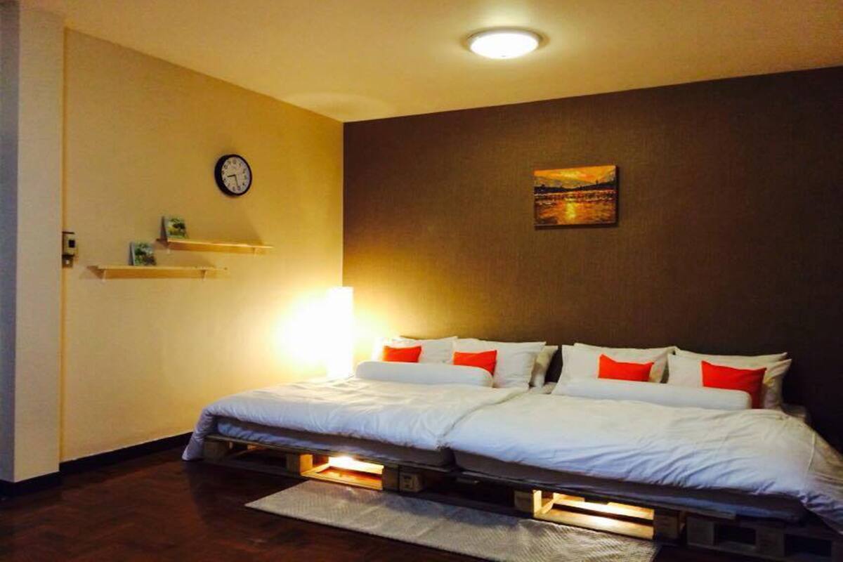 A bedroom with a bed, a clock, and a painting on the wall.