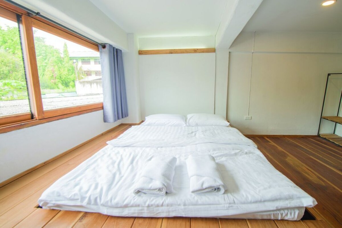 Una habitación con una cama grande, un ventanal con vistas a zonas verdes y suelo de madera.