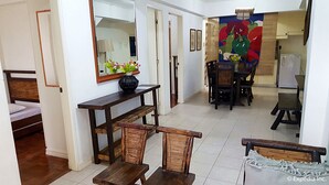 A room with a bed, a dining table with chairs, a mirror, and a colorful painting on the wall. - Baguio Vacation Apartments (Baguio)