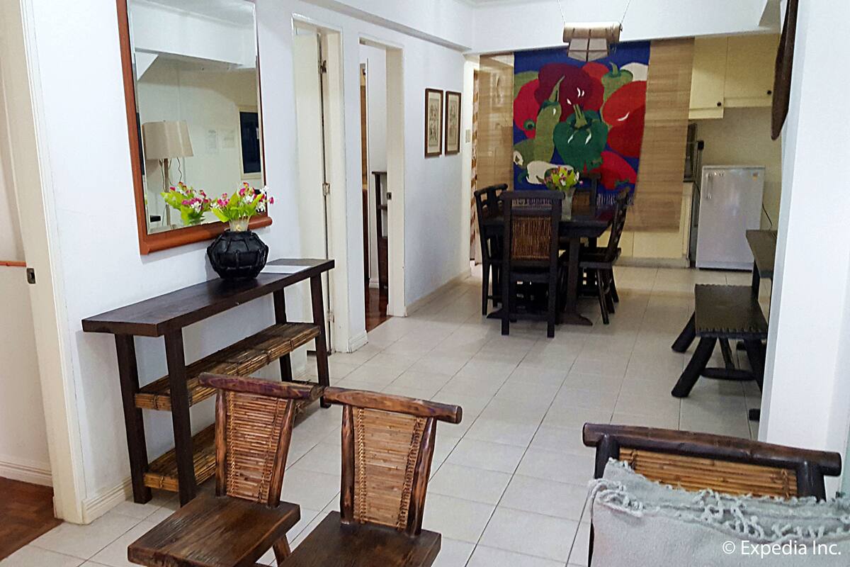 Una habitación con cama, una mesa de comedor con sillas, un espejo y un cuadro colorido en la pared.