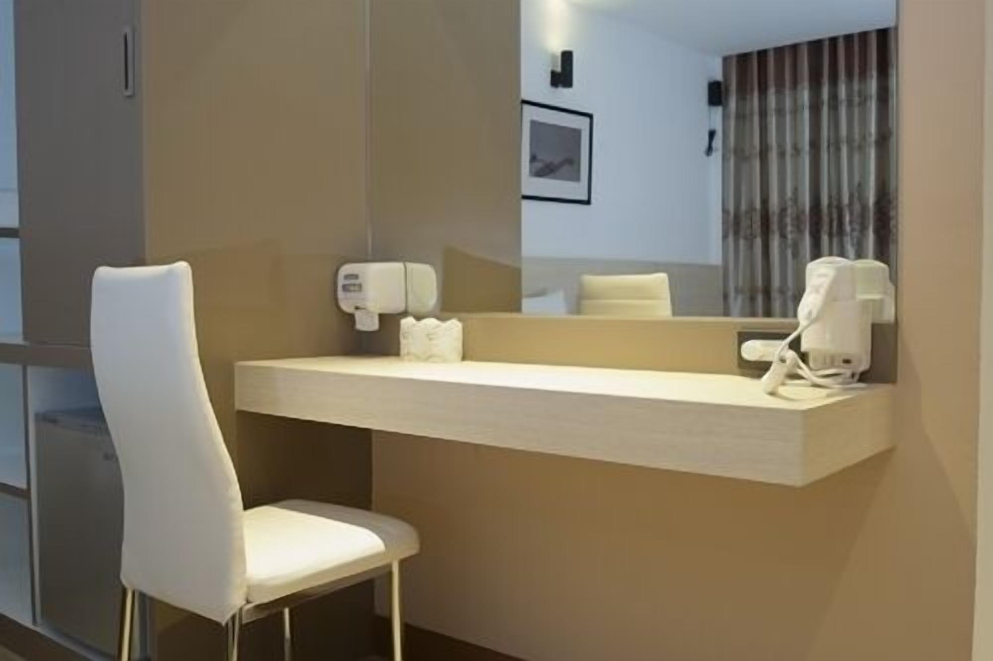 A modern bathroom with a white chair, a sink, a mirror, and a hand dryer.