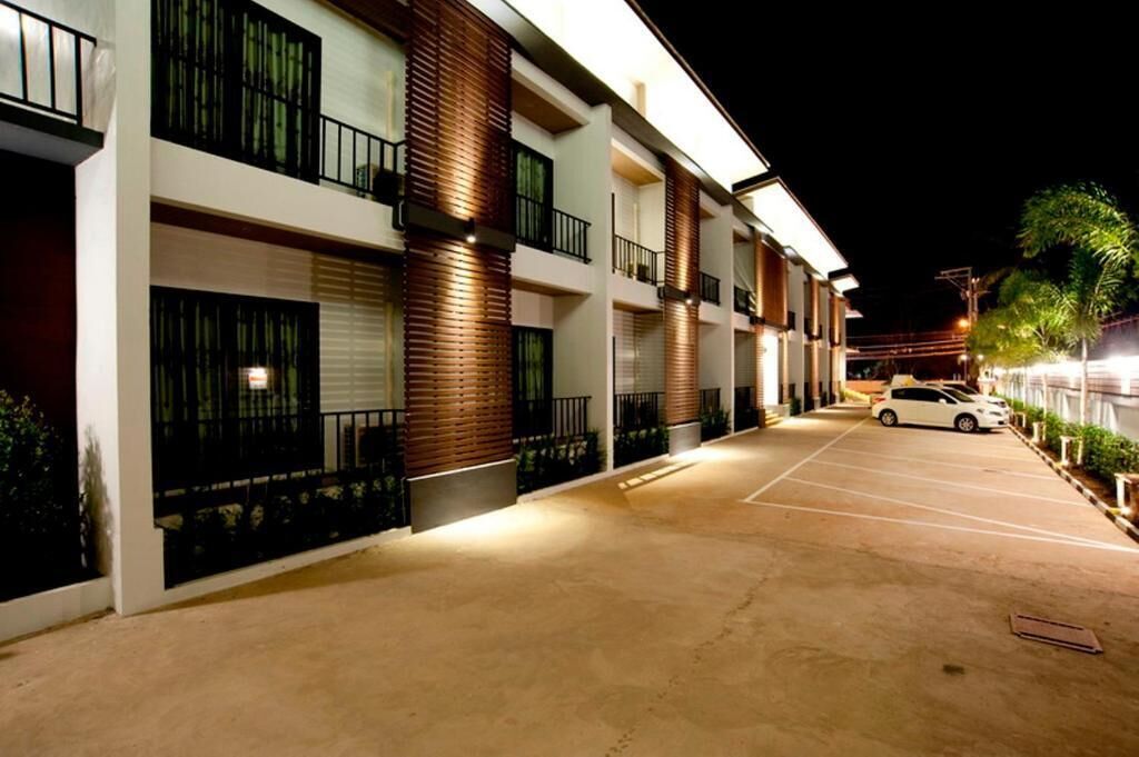 A multi-story hotel with a parking lot, featuring balconies with railings and a modern design.