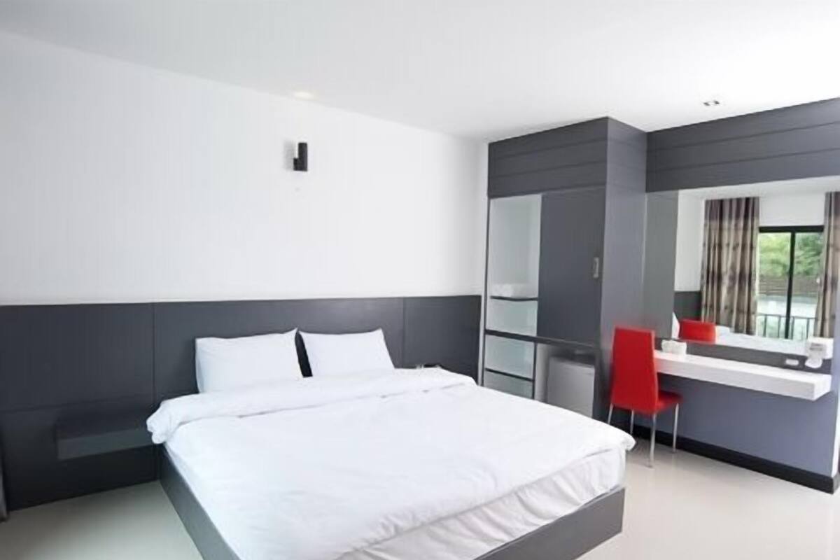 Une chambre d’hôtel moderne avec un grand lit, un bureau avec une chaise et un grand miroir.