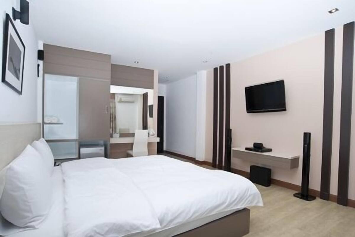 Une chambre d’hôtel avec un lit, un téléviseur fixé au mur et un miroir.