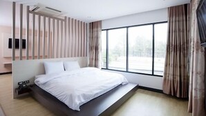 Un dormitorio moderno con cama, un ventanal y vistas al exterior.