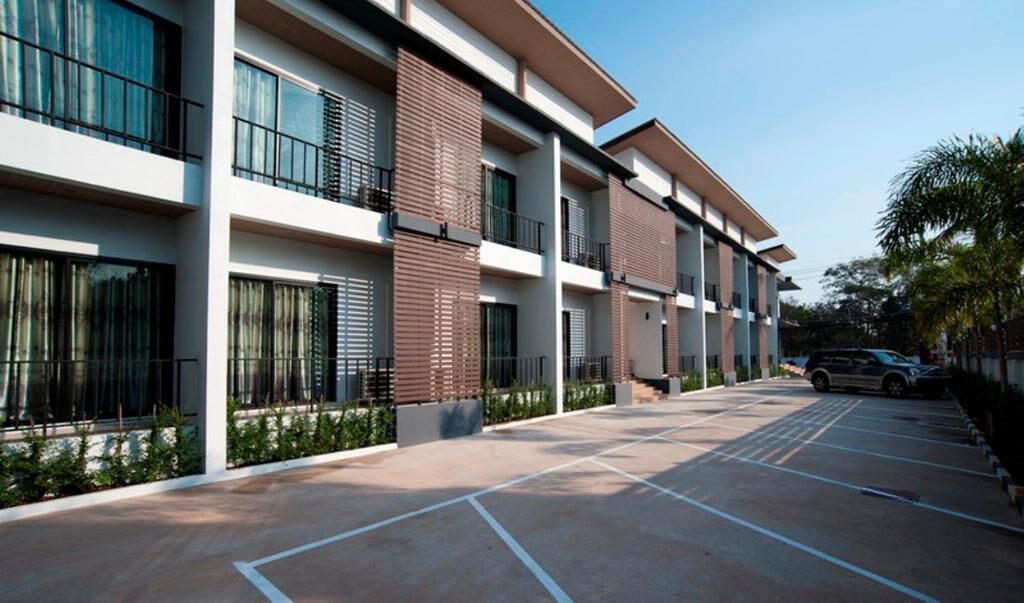 Un edificio moderno de varios pisos con un estacionamiento al frente.