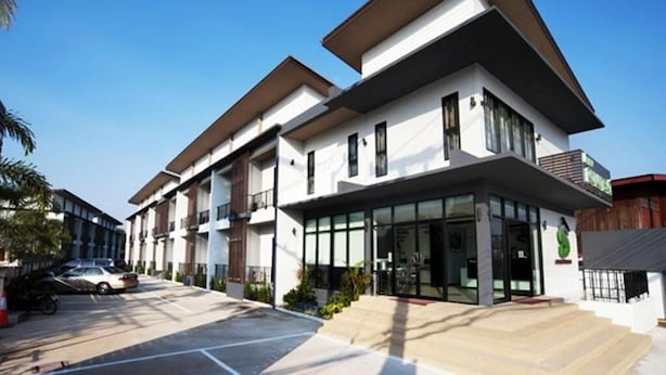 Un edificio moderno de varios pisos con techo plano, ventanas amplias y un área de entrada cubierta.