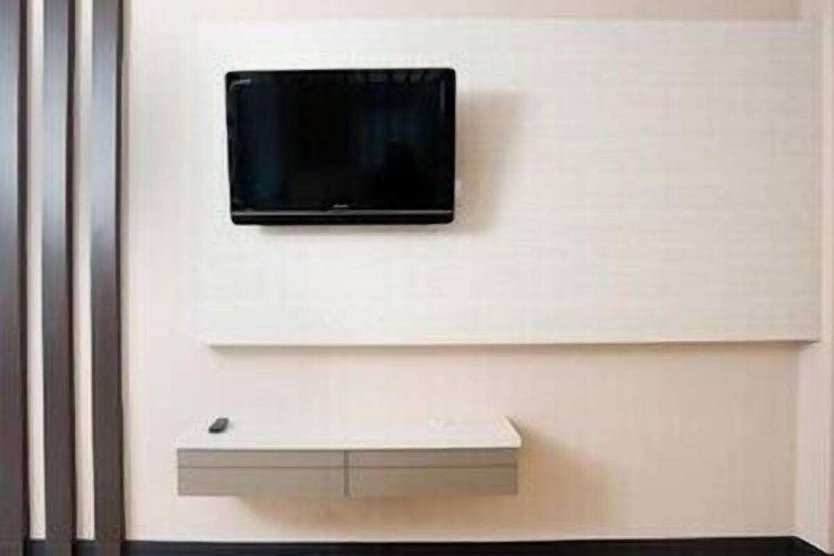 Un téléviseur fixé au mur et un meuble à pharmacie encastré.