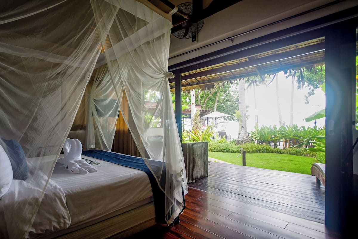 A bed with a canopy, a wooden floor, and a view of the outdoors.