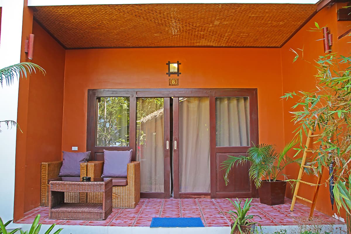 An entrance with a door, a wicker sofa, and a potted plant.