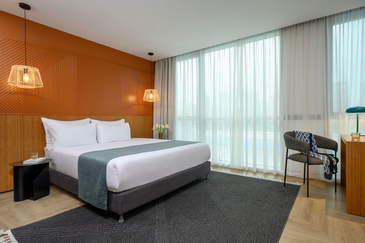 Une chambre d’hôtel moderne avec un grand lit, une table de chevet, une chaise et un bureau.