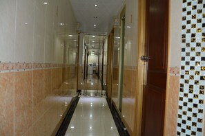 A corridor with reflective tiled floors, glass doors, and a patterned wall. - Everest Guest House (Kowloon)