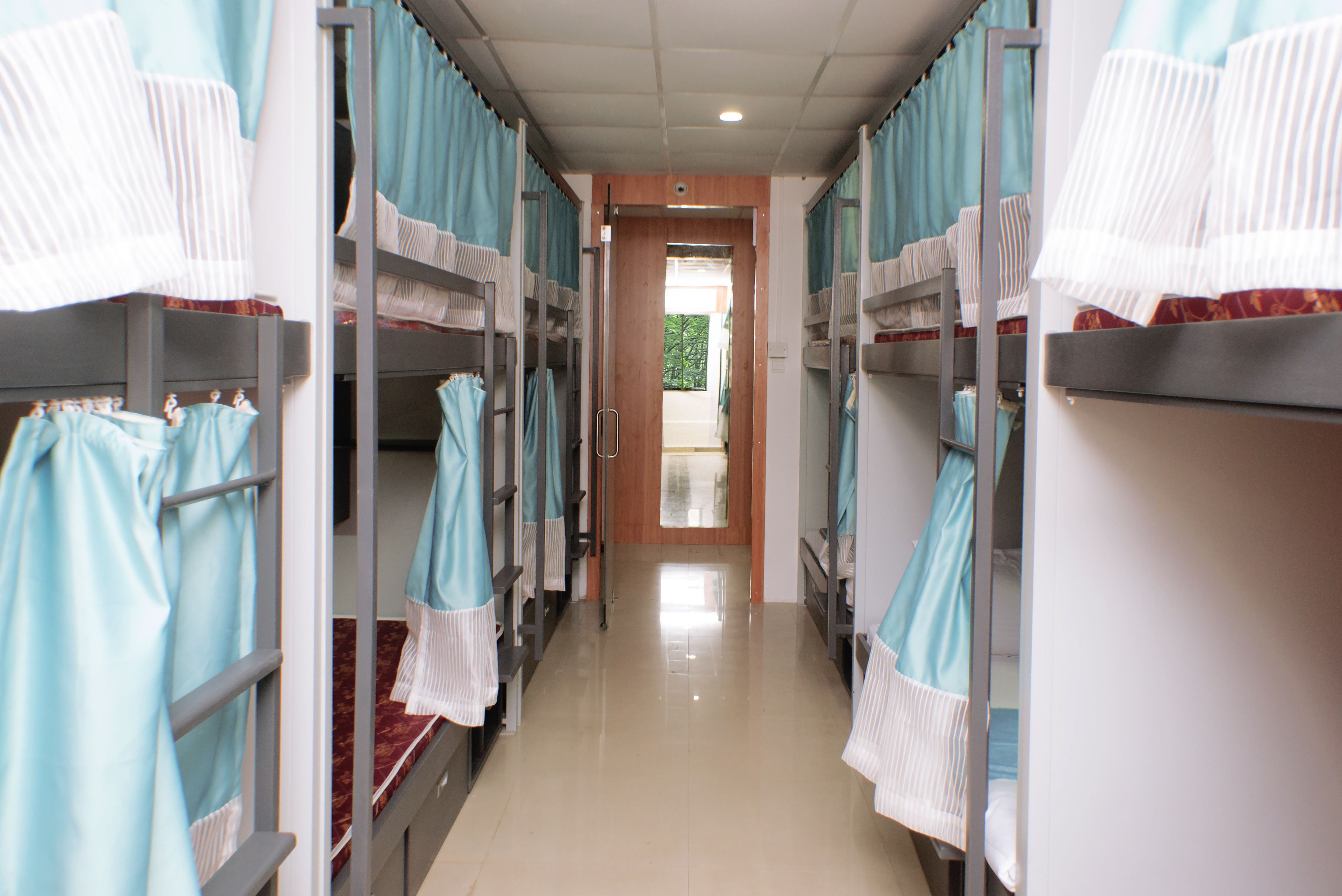A corridor with bunk beds, each with a towel hanging on the side.