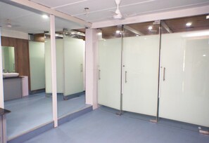 A hotel room with a large mirror, a ceiling fan, and a bathroom with a sink and mirror. - Arma Hostel Mumbai (Mumbai)