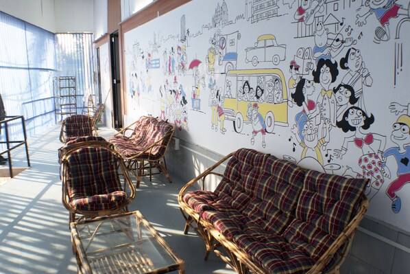 Una habitación con muebles de mimbre, un mural grande y vistas a través de una ventana.